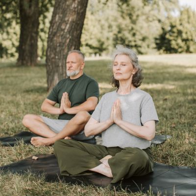 Meditation im Sitzen Ein Paar meditiert im Sitzen in der Natur auf einer Wiese