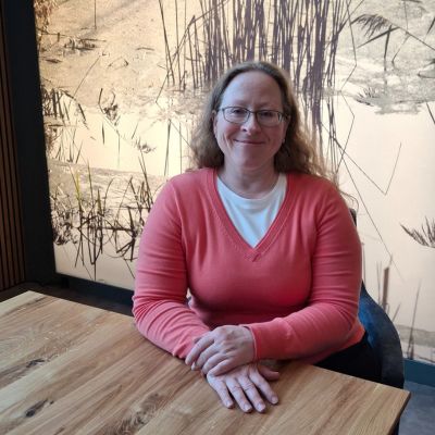 Melanie Frau am Tisch sitzend lächelt in die Kamera