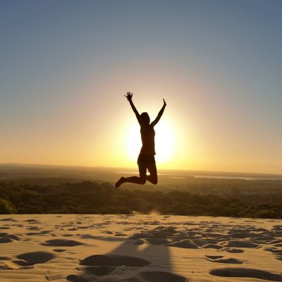 Person hüpft erfreut in die Luft am Strand