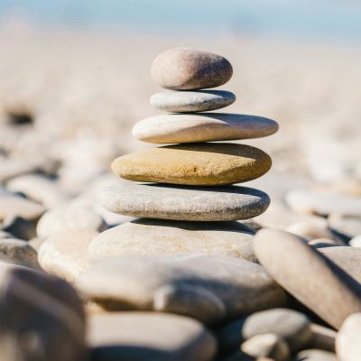 Gestapelte Kiesel am Strand als Bild für die aufeinander aufbauenden Phasen der More Vitality Methode